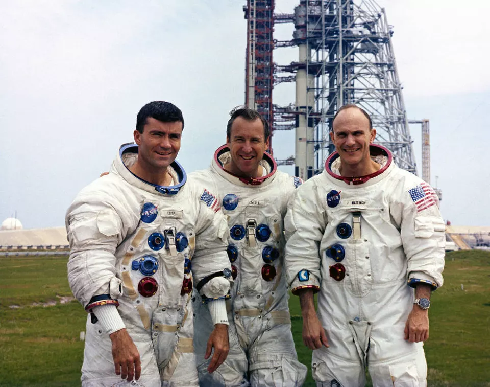 Arkada bir roket rampası, önde poz veren üç astronot