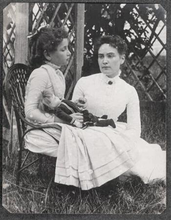 Kucağında bebek tutan küçük Helen Keller ve yanında oturan Anne Sullivan